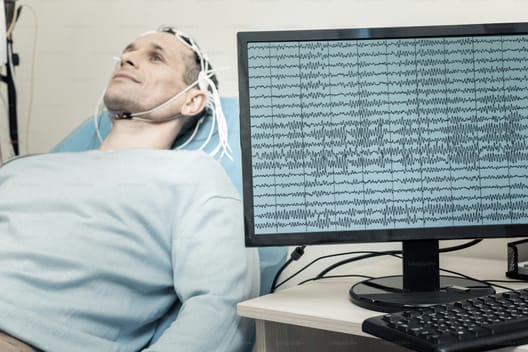 EEG în progres - pacient stând întins și un aparat care măsoară undele cerebrale